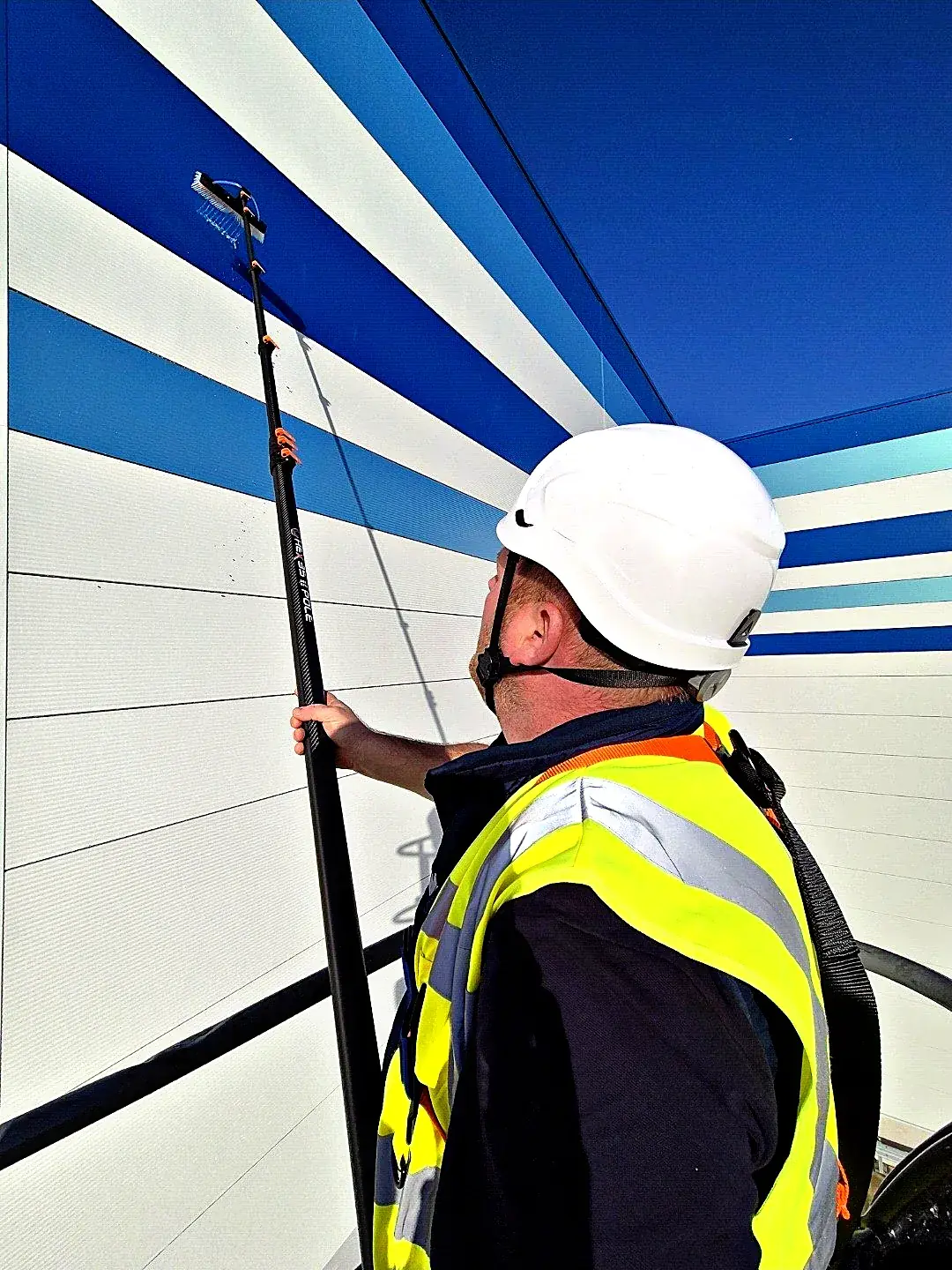 Cleaning high-level cladding with a water-fed pole