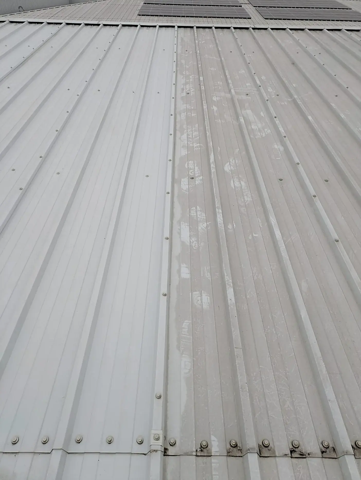 Warehouse roof half cleaned, showing the clean and dirty sheeting side by side